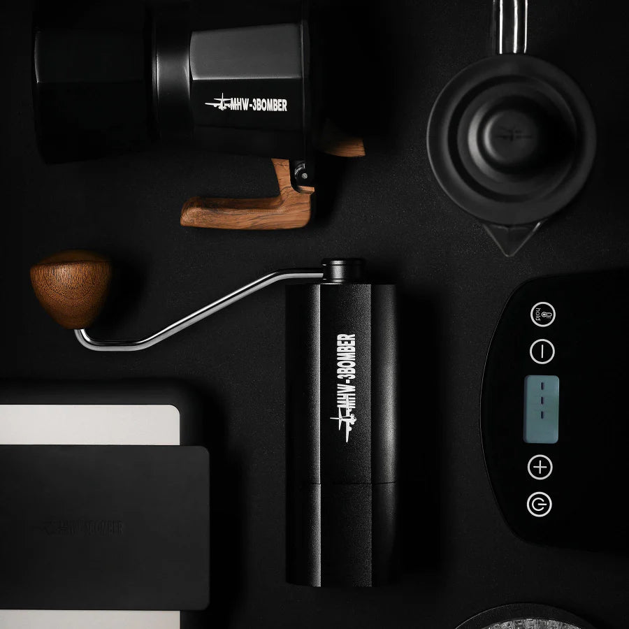 MHW-3BOMBER black manual coffee grinder with wooden handle and other coffee equipment.