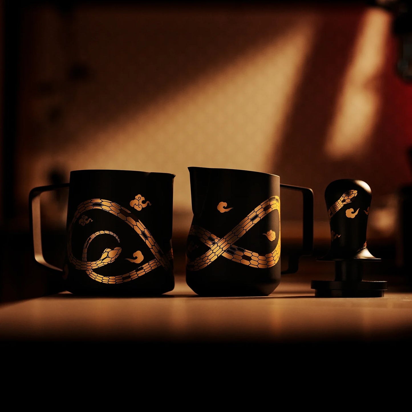 The MHW-3BOMBER Turbo Milk Pitcher-Year of the Snake Limited Edition set, in black with elegant gold swirl patterns, crafted from Austenitic 304 Stainless Steel, includes a milk frothing jug and tamper beautifully displayed under warm ambient lighting.