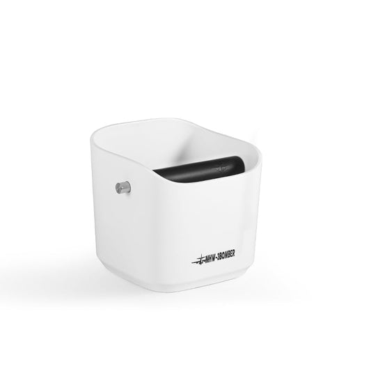 The MHW-3BOMBER Coffee Espresso Square Knock Box is white with a cylindrical top opening and black roller. Featuring a small metal pin on the side, it boasts the label WMW-SS0AMER on a durable surface set against a pristine white background. Ideal for coffee use.