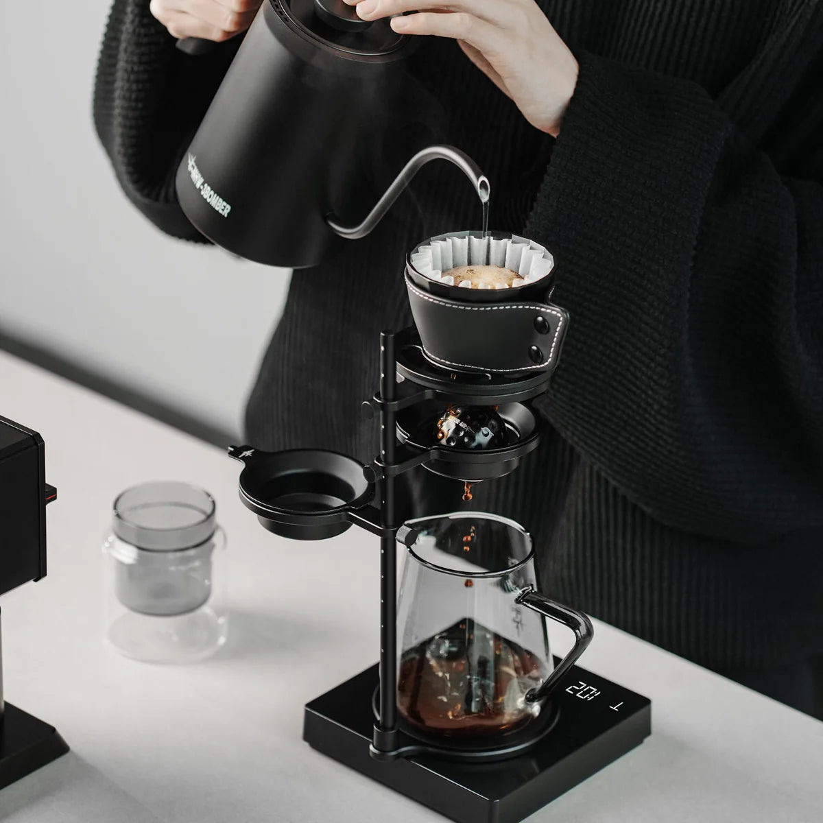 Pour-over brewing kit in use. Black stand, leather dripper. Coffee being brewed. Brew Starter Kit.