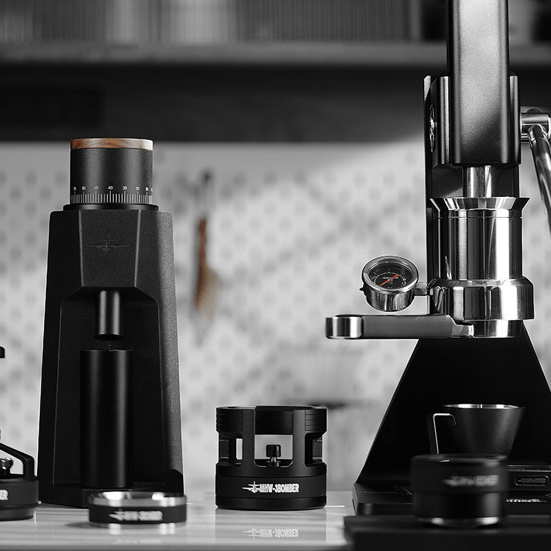 MHW-3BOMBER coffee setup: grinder, portafilter holder, and lever espresso machine. Black and silver, professional barista tools.