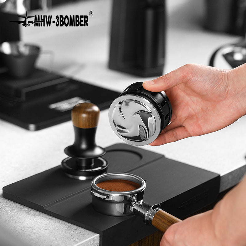 MHW-3BOMBER coffee distributor & tamper on mat. Black/silver gravity adaptive tool on counter.