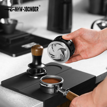 MHW-3BOMBER coffee distributor & tamper on mat. Black/silver gravity adaptive tool on counter.