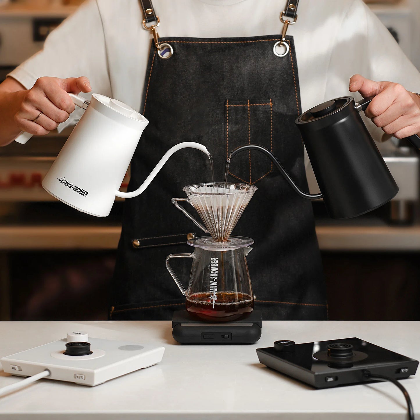 MHW-3BOMBER gooseneck kettles in white and black being used to pour hot water through a coffee filter.