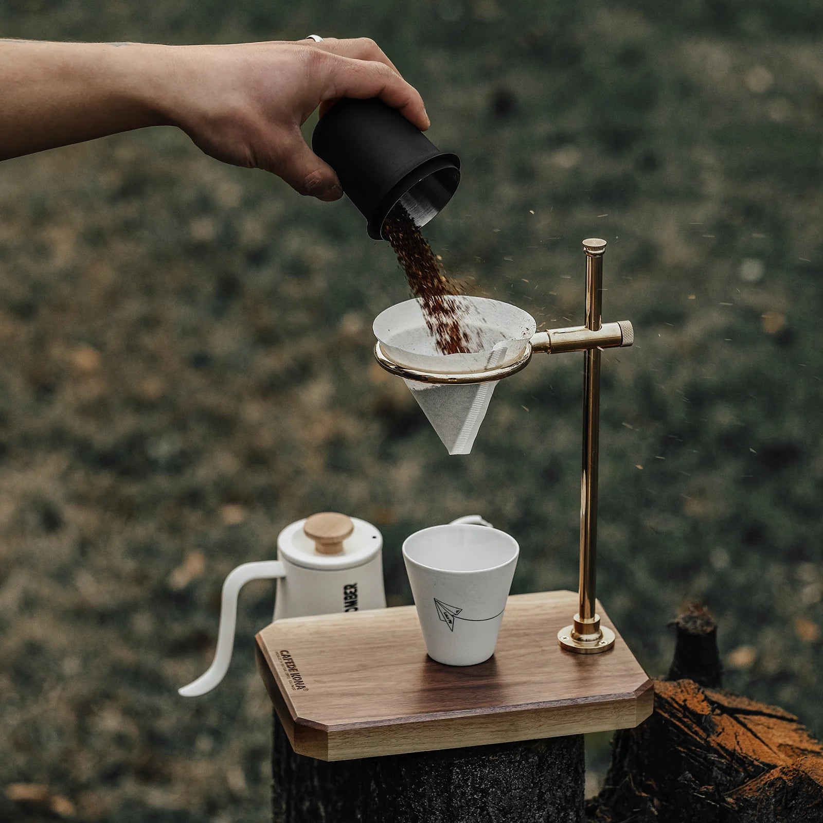 MHW-3BOMBER coffee setup: Pour-over stand, server, and cup on wood tray. Paper filter in use. 