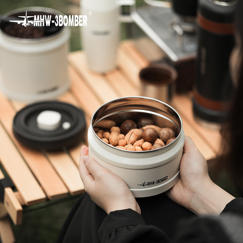 MHW-3BOMBER vacuum canister. Beige color. Airtight coffee storage shown on wooden table with nuts inside.