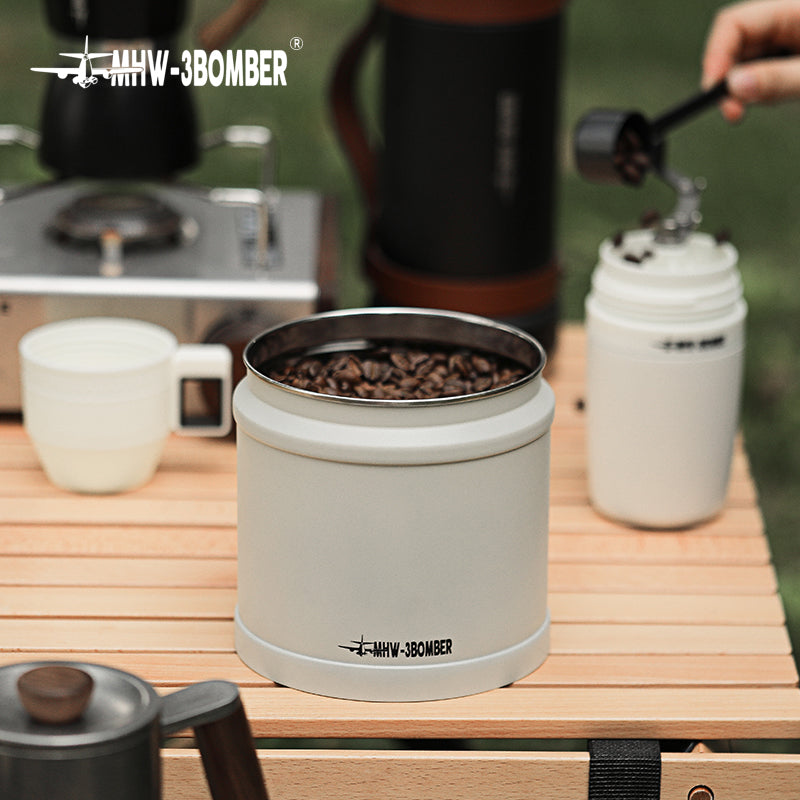 MHW-3BOMBER white vacuum storage canister with coffee beans inside, on a wood table. Fresh coffee.