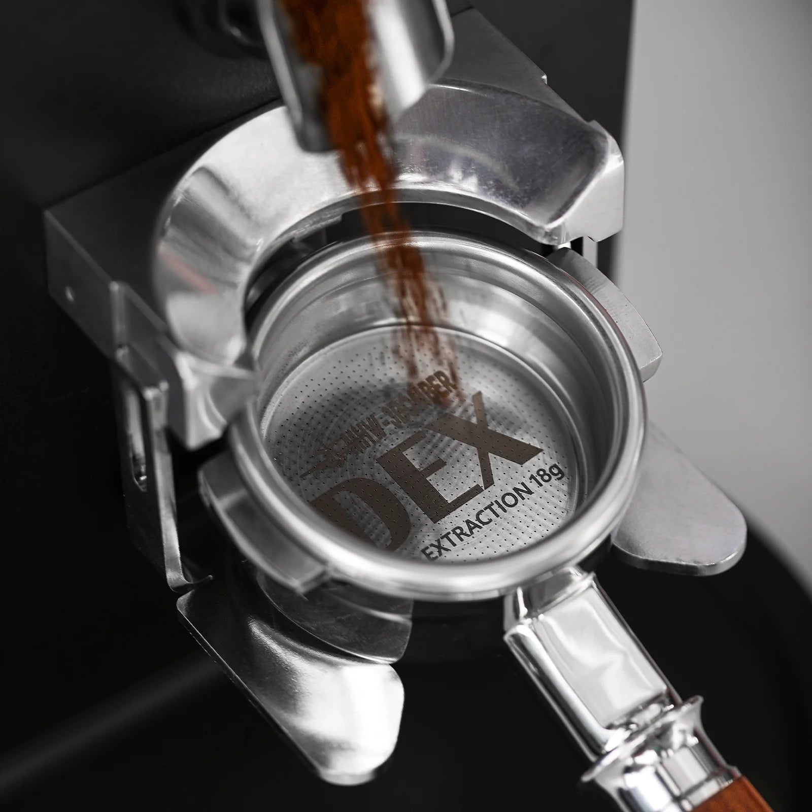 MHW-3BOMBER DEX 58mm filter basket being filled with ground coffee. Silver stainless steel finish.
