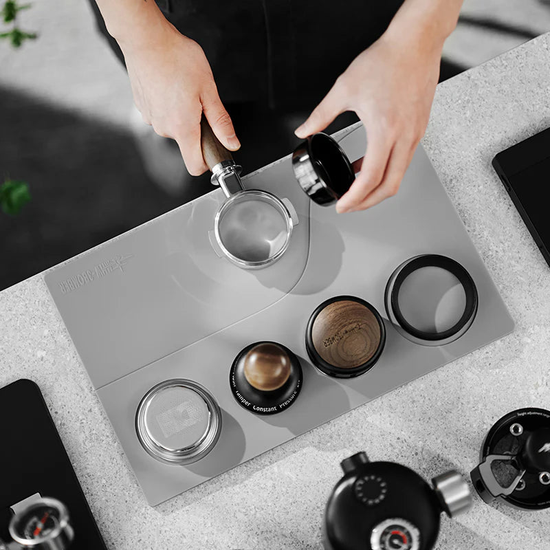 MHW-3BOMBER gray silicone tamping base with portafilter, tamper, and distributor slots. Coffee accessories included.