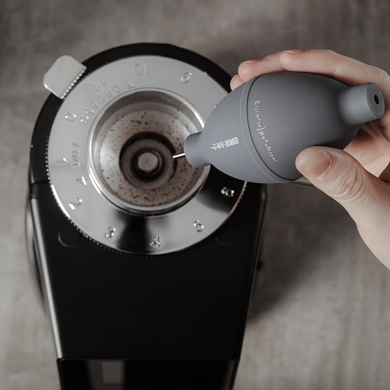 Coffee Air Blower cleaning a grinder. Gray blower with stainless steel nozzle. Daily Cleaning Essentials Kit item.