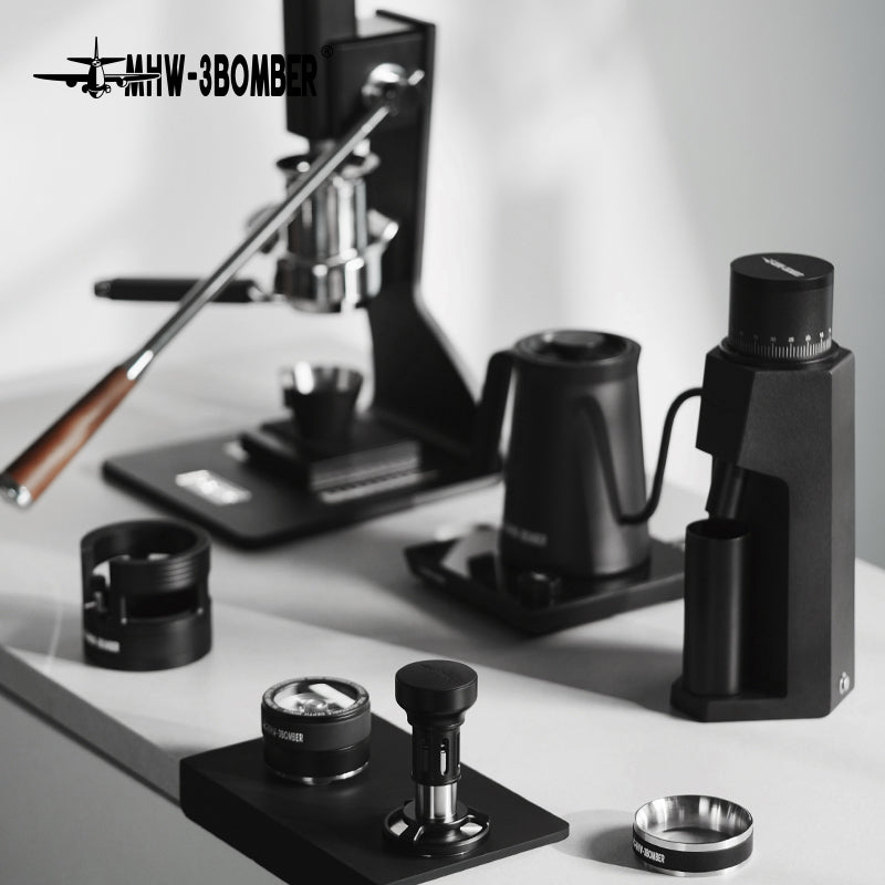 MHW-3BOMBER espresso setup: manual press, grinder, kettle, and tamper. Black finish. 