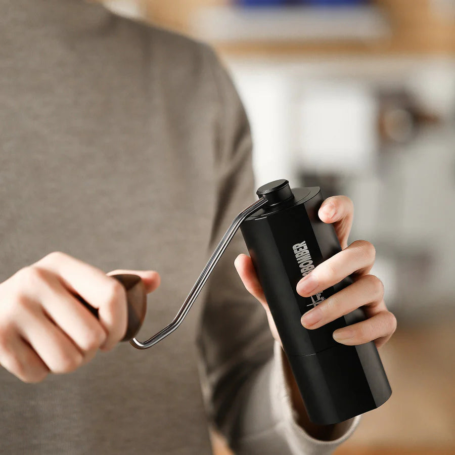 MHW-3BOMBER black manual coffee grinder in use. Seven star stainless steel burr & magnetic design visible.