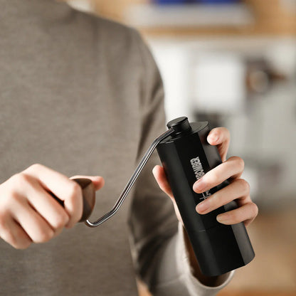 MHW-3BOMBER black manual coffee grinder in use. Seven star stainless steel burr & magnetic design visible.