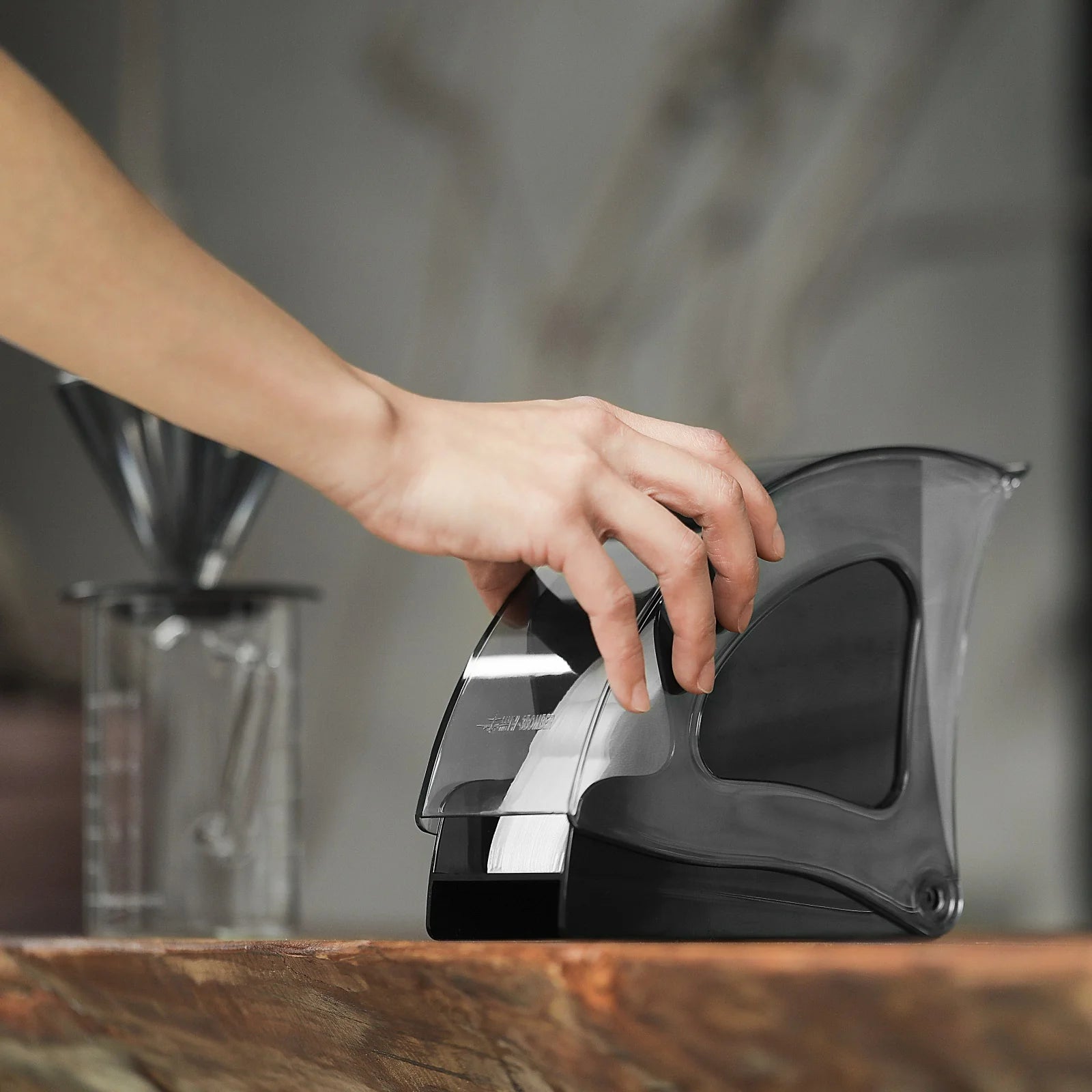 MHW-3BOMBER coffee filter holder, clear plastic with black base, holding filters. Kitchen setting.