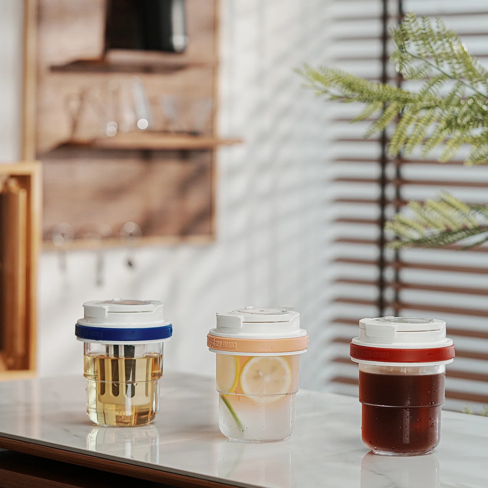 MHW-3BOMBER Cold Brew Cups: clear bodies, blue, orange, red lids. Beverages inside, showing filter. Portable, leak-proof.