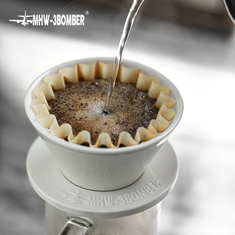 MHW-3BOMBER Meteor Coffee Dripper being used. White ceramic dripper with coffee and filter. Water is being poured in.