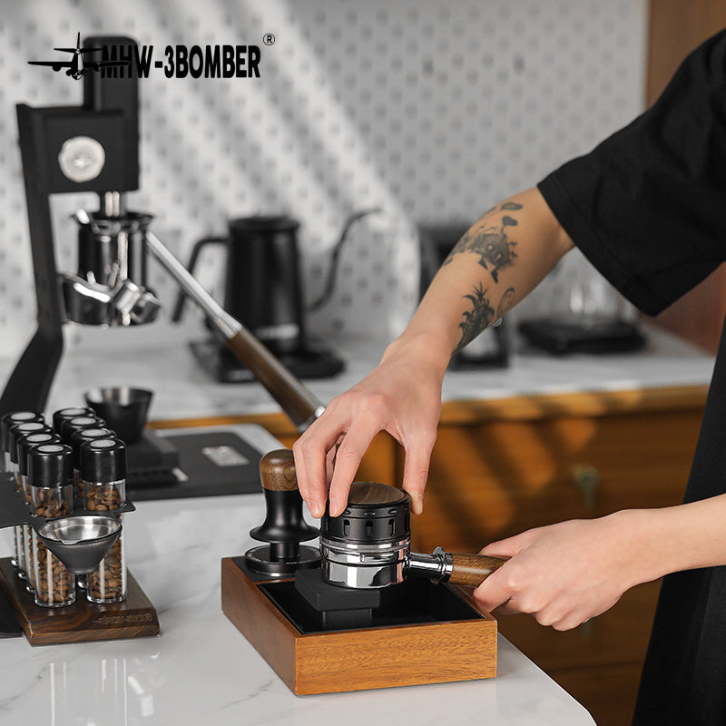 MHW-3BOMBER coffee distributor with wood base and portafilter on a counter. Falcon gravity system for espresso extraction.