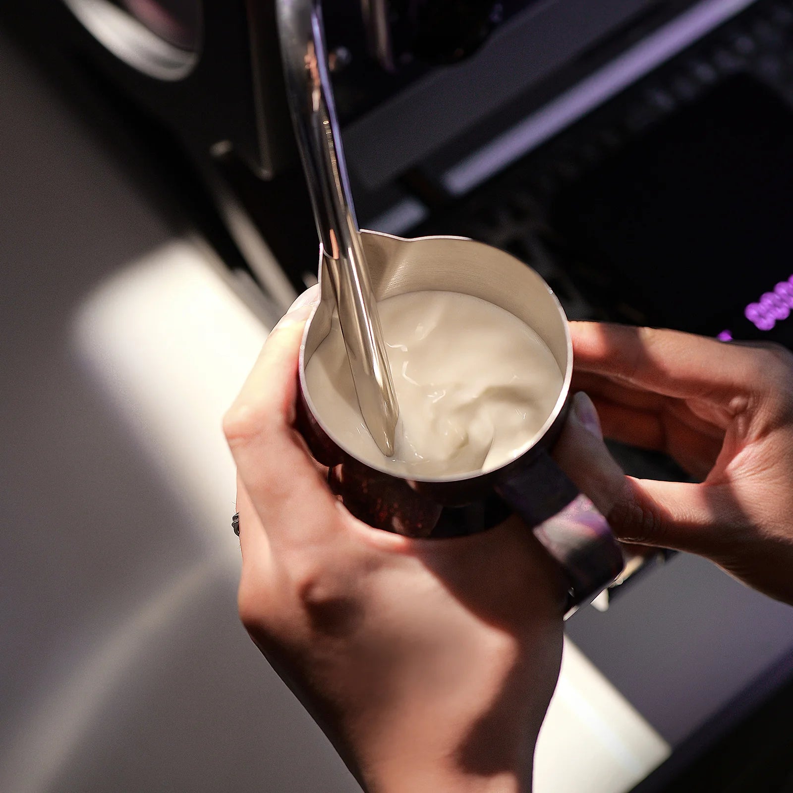 MHW-3BOMBER purple latte art pitcher with crocodile spout, being used to froth milk.