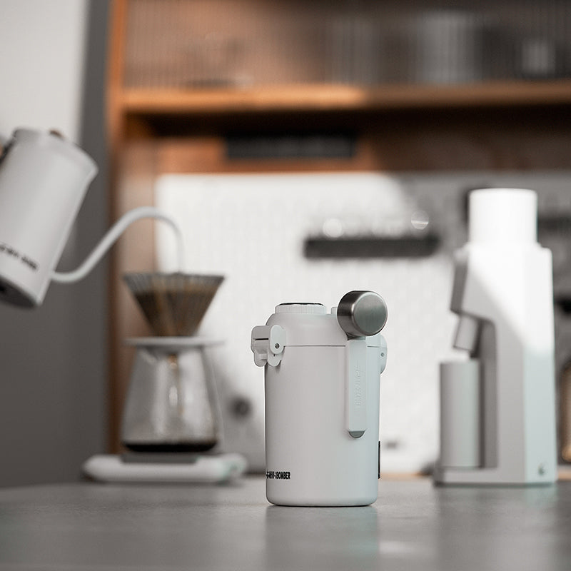 MHW-3BOMBER white sealed canister with measuring spoon. Coffee brewing setup on counter.