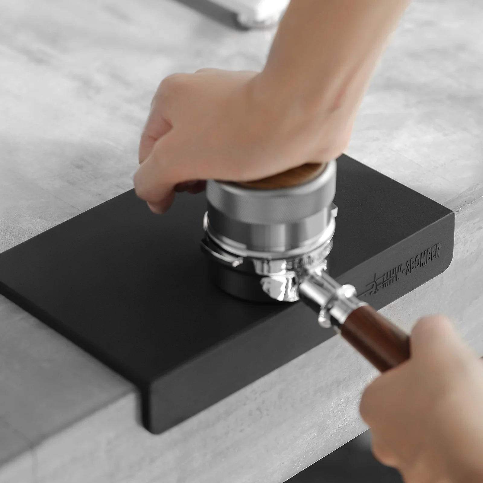 MHW-3BOMBER black silicone coffee tamper mat on counter being used to tamp espresso. 