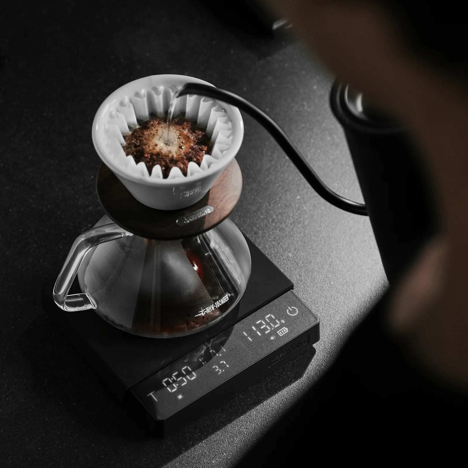 MHW-3BOMBER Cube Coffee Scale brewing coffee, black. Shows time and flow rate. On kitchen counter.