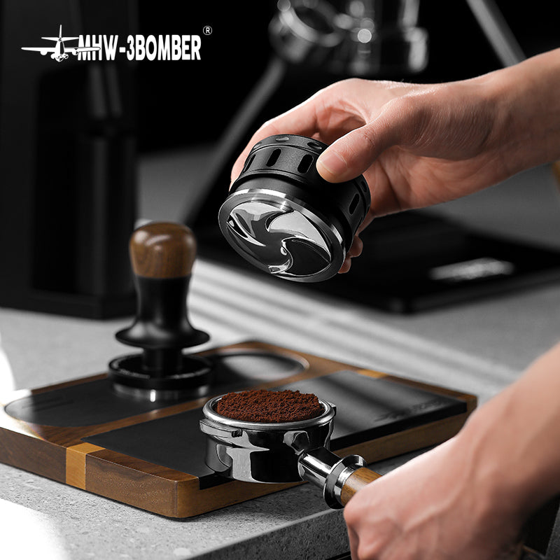 MHW-3BOMBER Falcon coffee distributor in black, shown with portafilter and tamper. Improves espresso extraction.