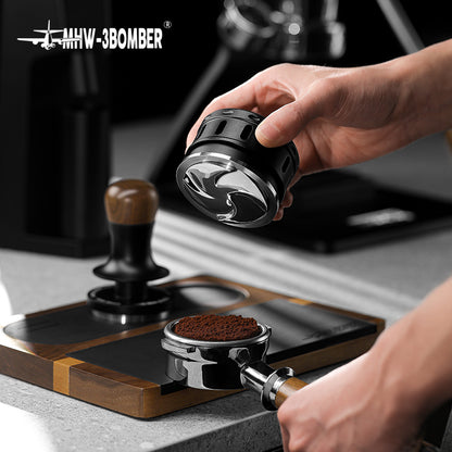 MHW-3BOMBER Falcon coffee distributor in black, shown with portafilter and tamper. Improves espresso extraction.