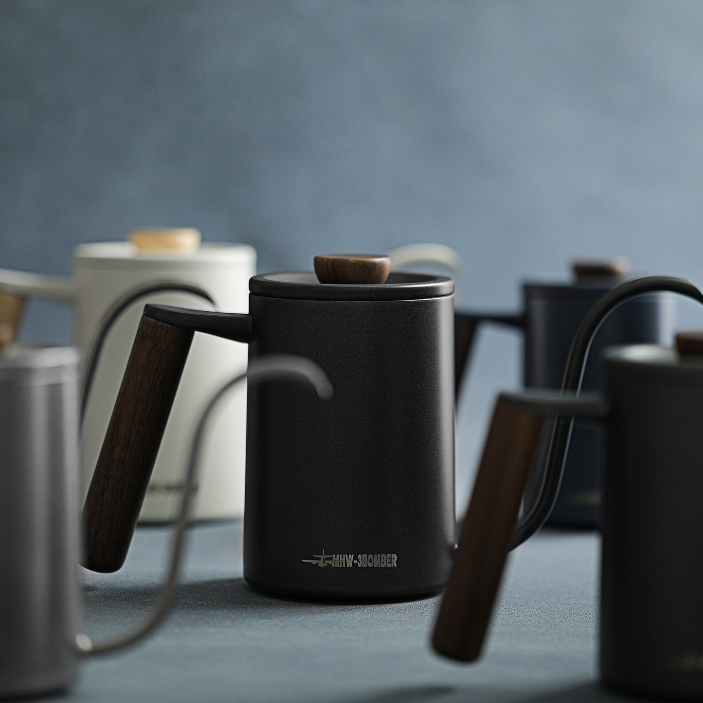 The MHW-3BOMBER Planet Hand Brewing Kettle collection, with sleek wooden-handled designs, elegantly features in a soft focus setting. A central black gooseneck kettle exemplifies minimalist aesthetics, perfect for drip coffee enthusiasts.