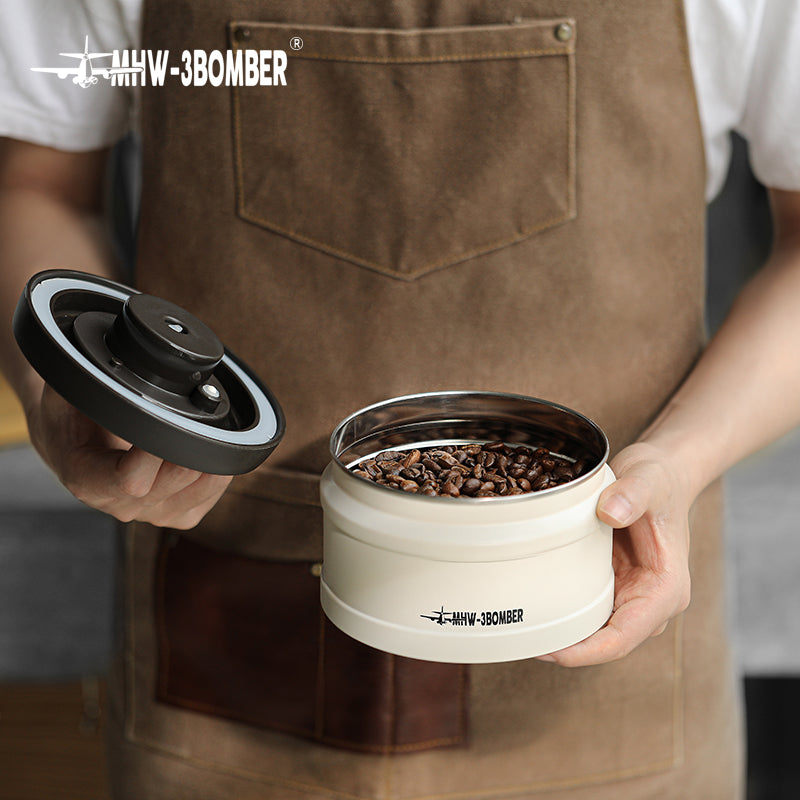 MHW-3BOMBER cream vacuum canister with lid off, filled with coffee beans. Freshness-keeping container.