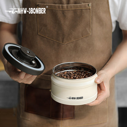 MHW-3BOMBER cream vacuum canister with lid off, filled with coffee beans. Freshness-keeping container.