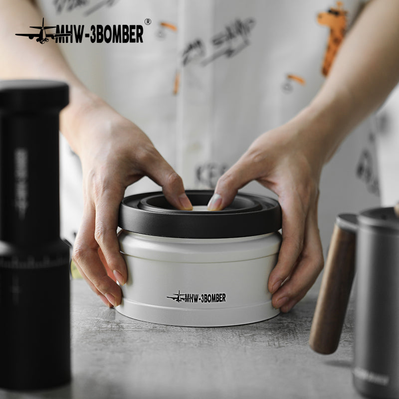 MHW-3BOMBER vacuum coffee canister. White with black lid. Prominent logo. Airtight for freshness.