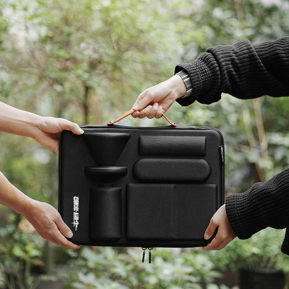 MHW-3BOMBER black portable pour-over set in case, being held by 2 sets of hands. Coffee brewing gear.