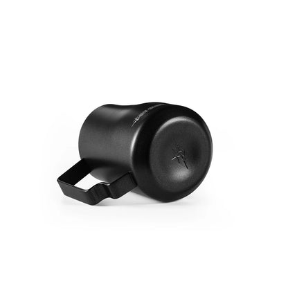 The MHW-3BOMBER Turbo Milk Pitcher in matte black, crafted from SUS 304 stainless steel, features a left-facing handle and stylized insect logo on the bottom. Its modern design is ideal for latte art creation.