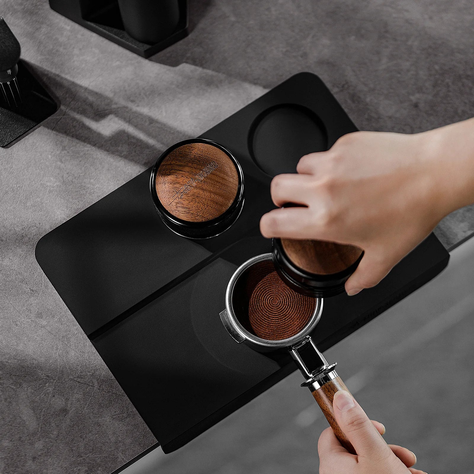 MHW-3BOMBER black silicone tamper mat with two holes, wood tamper, and portafilter. 