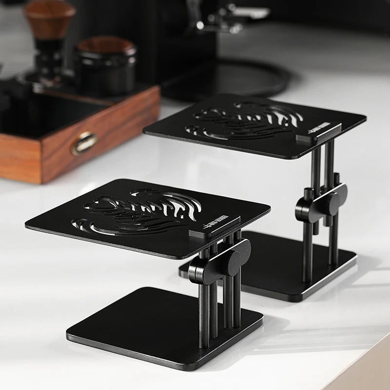MHW-3BOMBER black adjustable coffee scale stand with non-slip base on a countertop. 