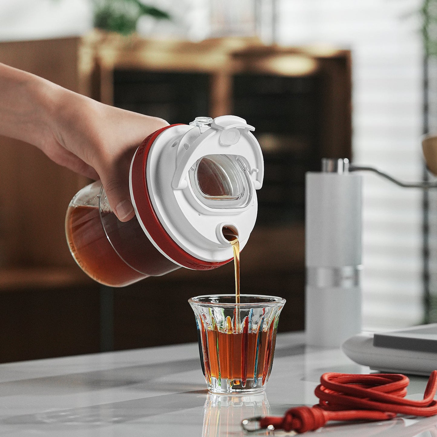 MHW-3BOMBER red cold brew cup being poured into a glass. Portable, leak-proof, and durable BPA-free Tritan material.