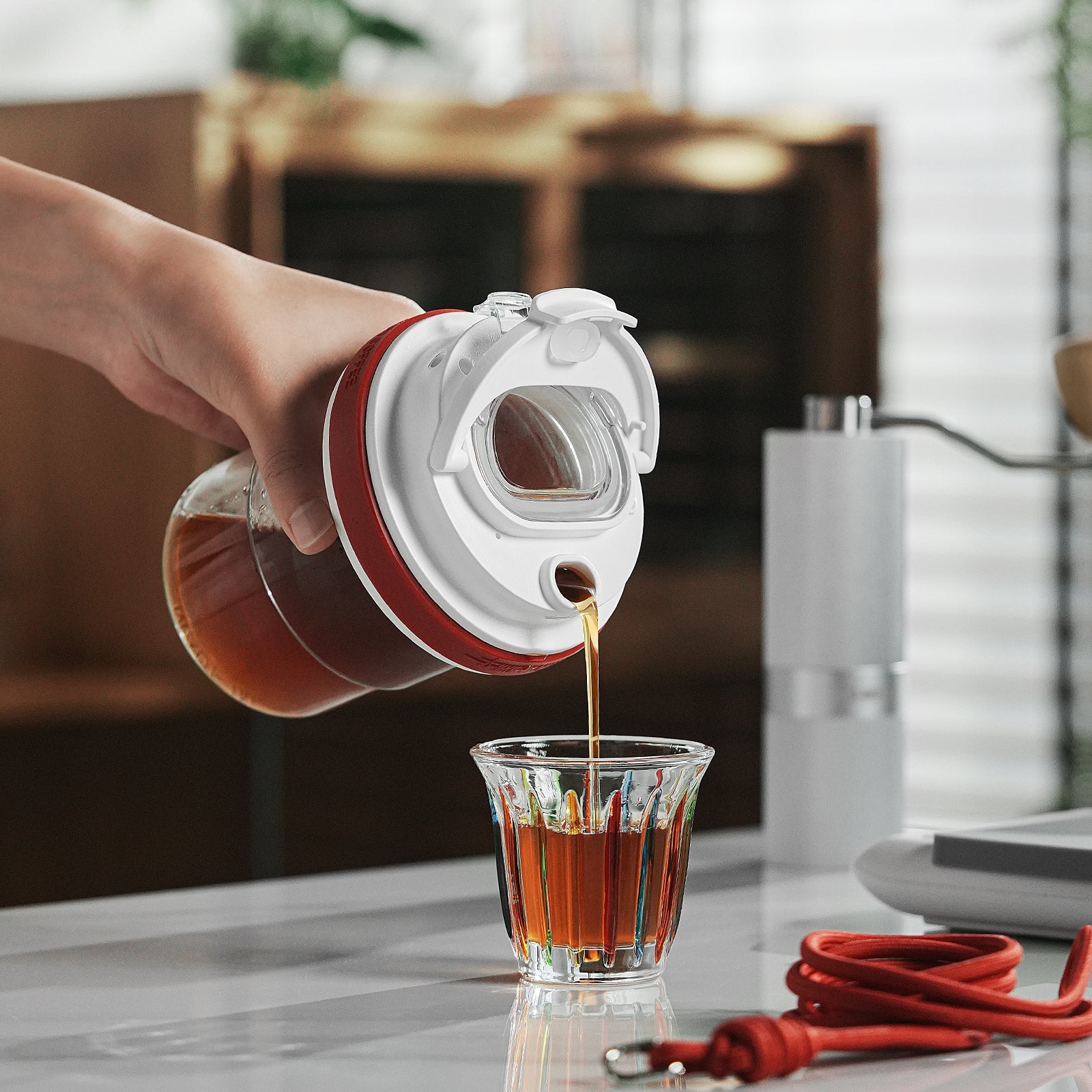 MHW-3BOMBER red cold brew cup being poured into a glass. Portable, leak-proof, and durable BPA-free Tritan material.