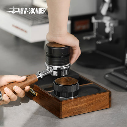 MHW-3BOMBER espresso tamping station with portafilter on a wood knock box.  