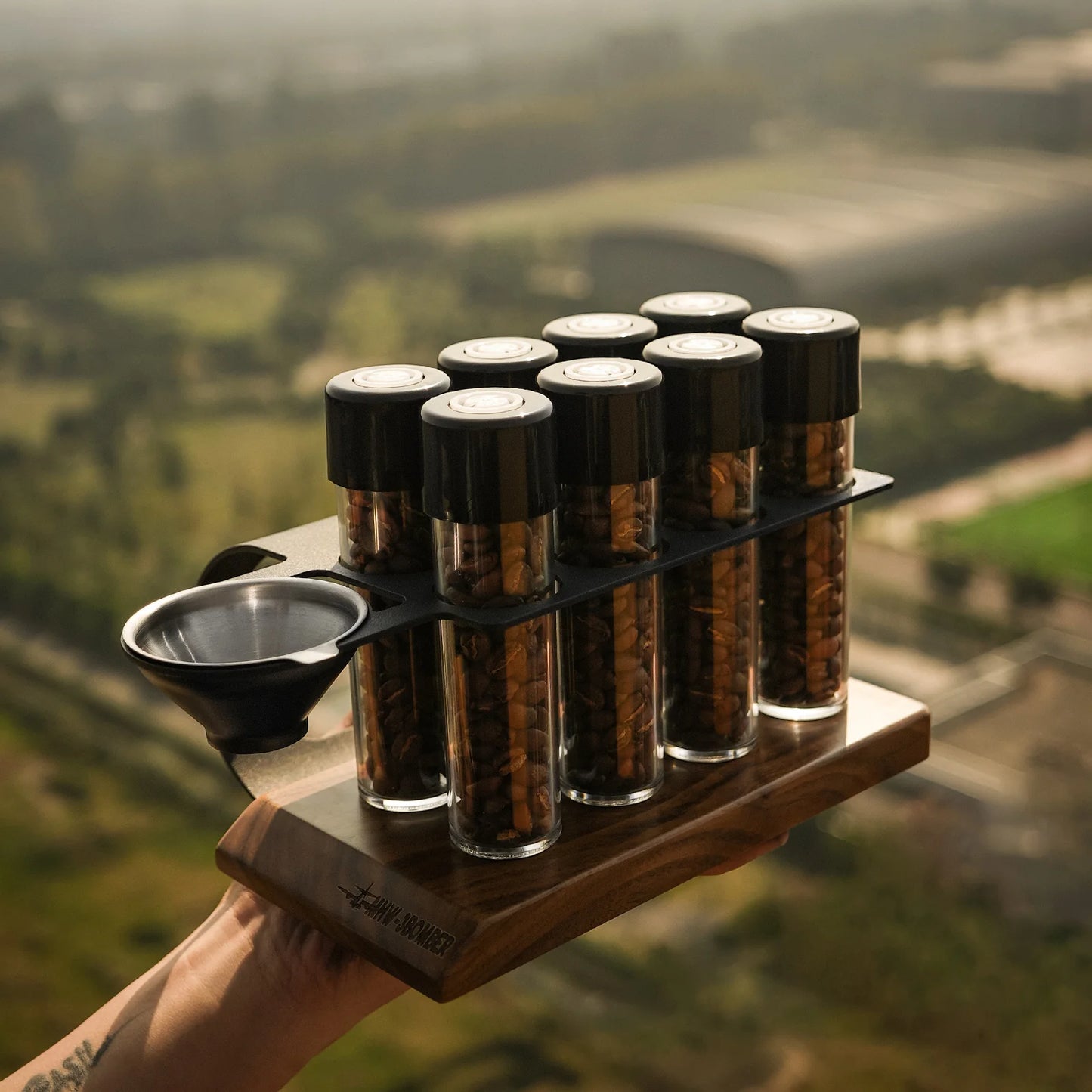 MHW-3BOMBER coffee energy tubes set. Glass vials with beans in wood stand. Metal funnel on the left. 