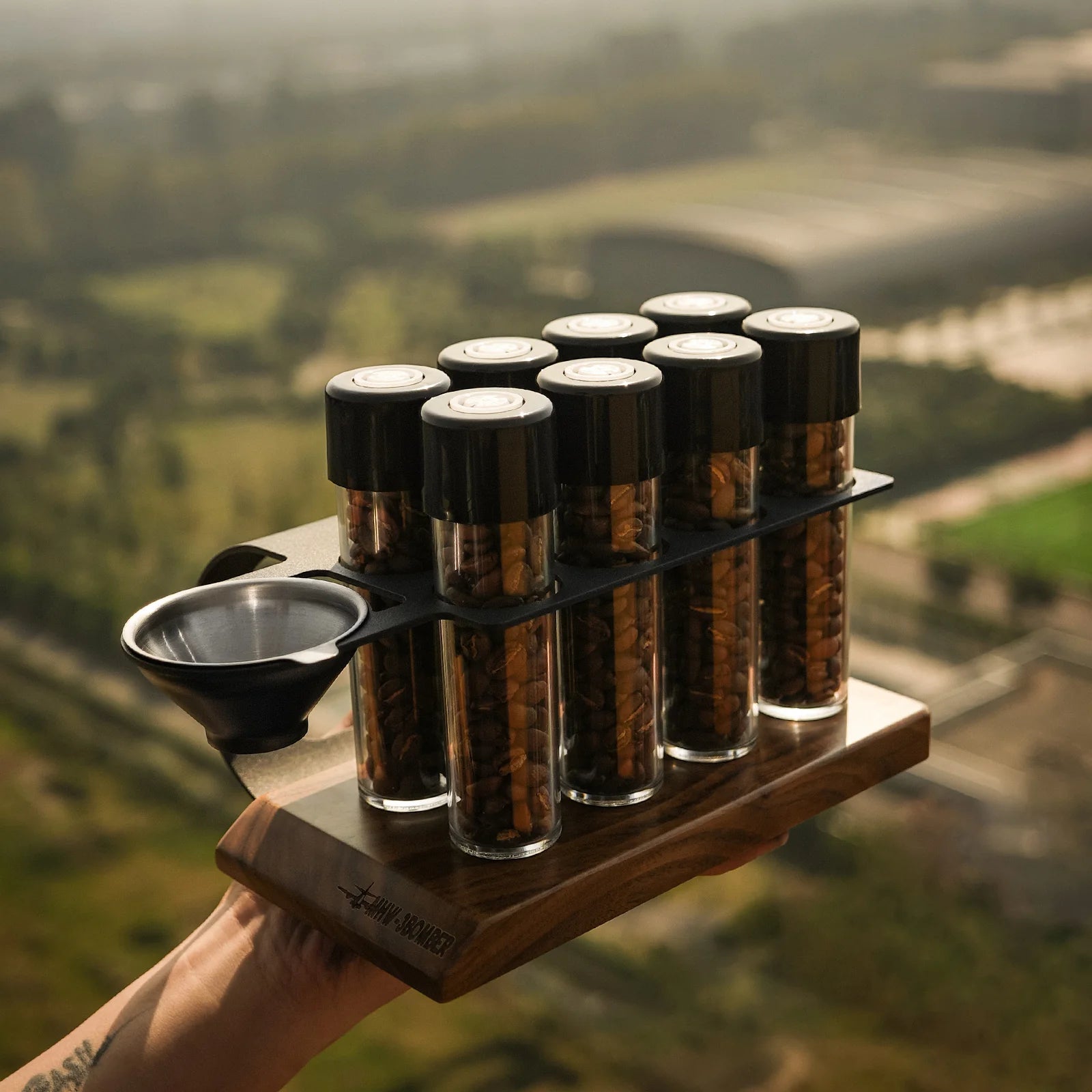 MHW-3BOMBER coffee energy tubes set. Glass vials with beans in wood stand. Metal funnel on the left. 