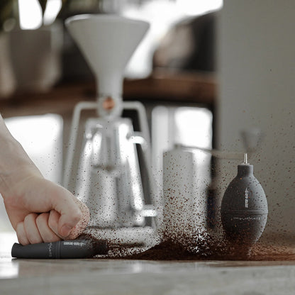 MHW-3BOMBER grey coffee air blower cleaning grounds on a counter. Filter, stainless nozzle.