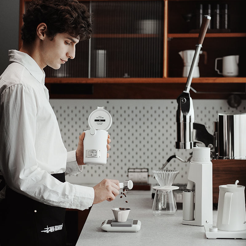 MHW-3BOMBER white Gambo Sealed Coffee Canister being used on counter. One-way valve, date discs, magnetic spoon feature.