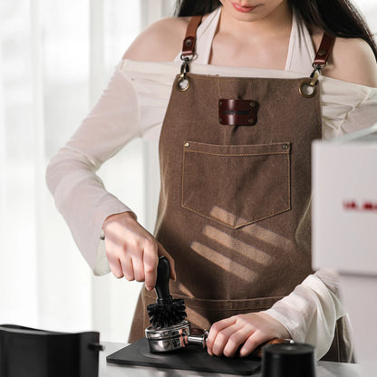 MHW-3BOMBER brush cleaning portafilter. Brown apron with leather detail. Cleaning espresso machine.