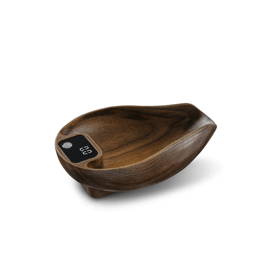 The MHW-3BOMBER Ovo Coffee Scale & Spray Bottle Set features a wooden, leaf-shaped digital coffee scale with a small display screen, natural wood grain finish, and curved edges—perfect for brewing and adding a stylish rustic touch to your kitchen.