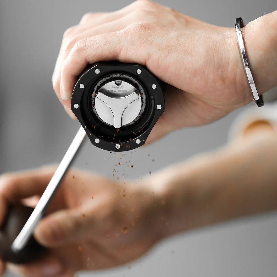 MHW-3BOMBER Adder V3 manual coffee grinder in black, shown grinding with point-to-point adjustment. 