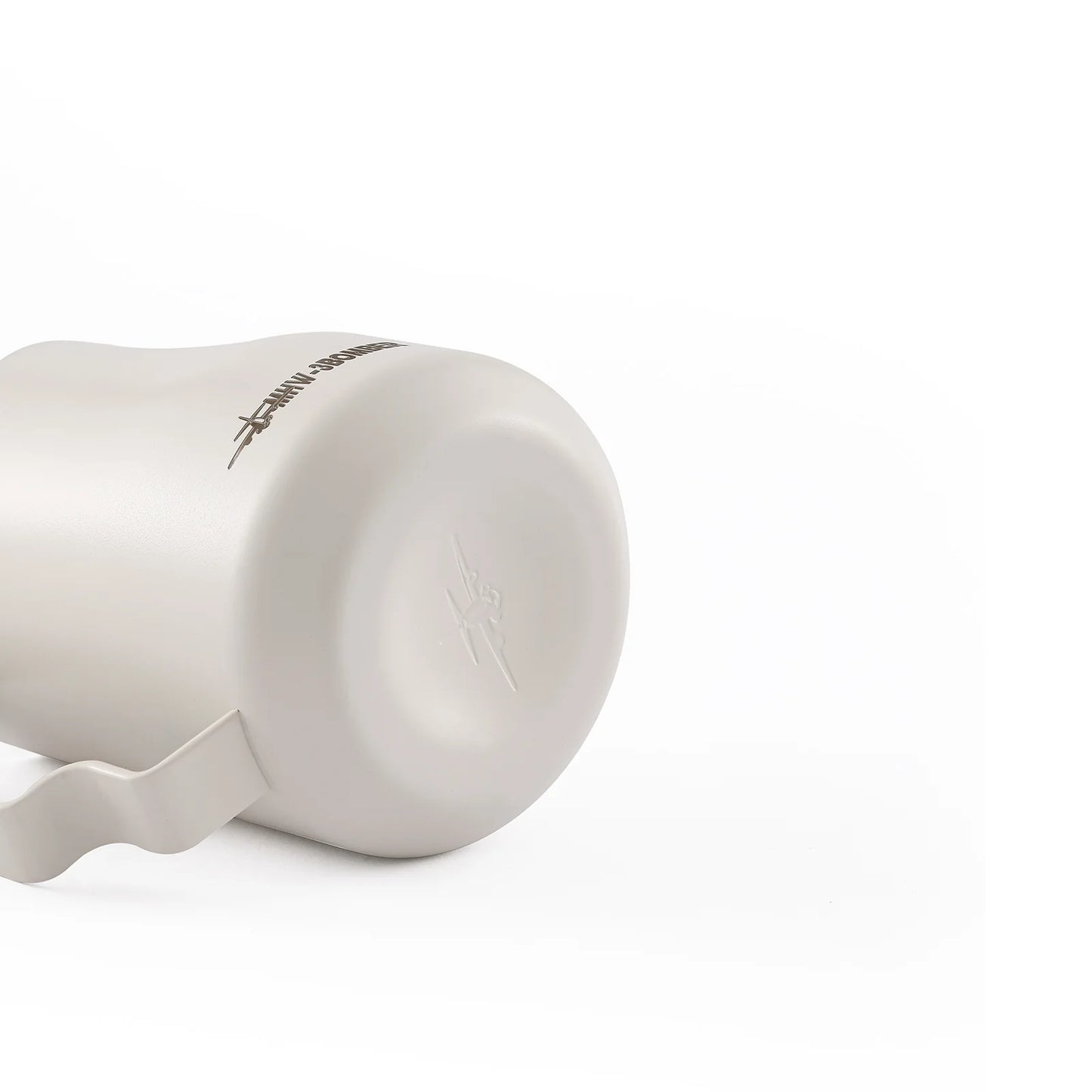 A stainless steel MHW-3BOMBER Turbo Milk Pitcher White lies on its side against a white background, ideal for milk frothing and latte art. It features a handle and has an embossed design with text near the base.