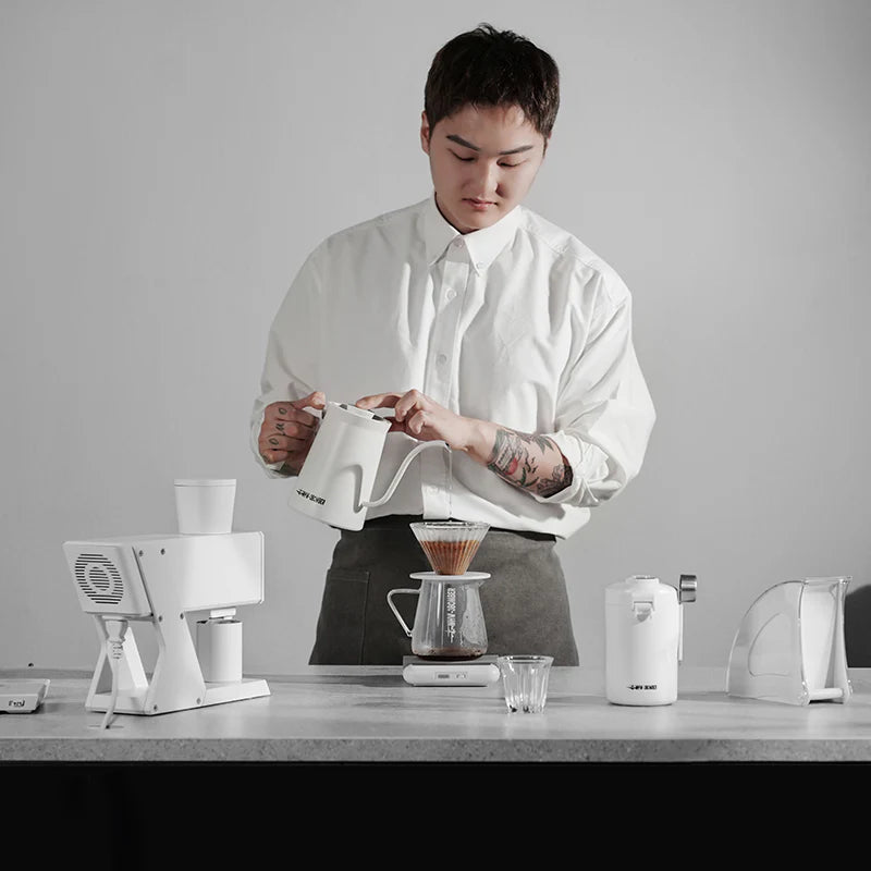 MHW-3BOMBER coffee grinder setup. White electric grinder and kettle. Brewing pour-over coffee.