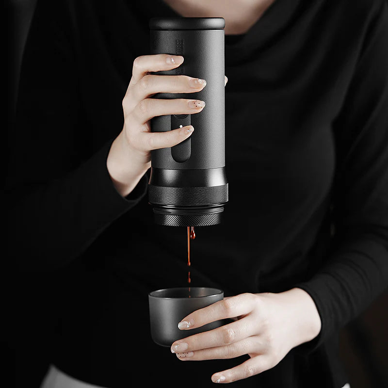 Person pouring coffee from a portable coffee maker into a cup.