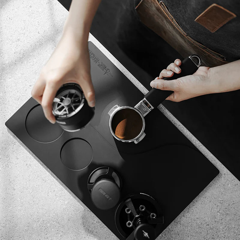 MHW-3BOMBER black silicone tamping base with portafilter, tamper, and WDT tool slots. For organized coffee station.