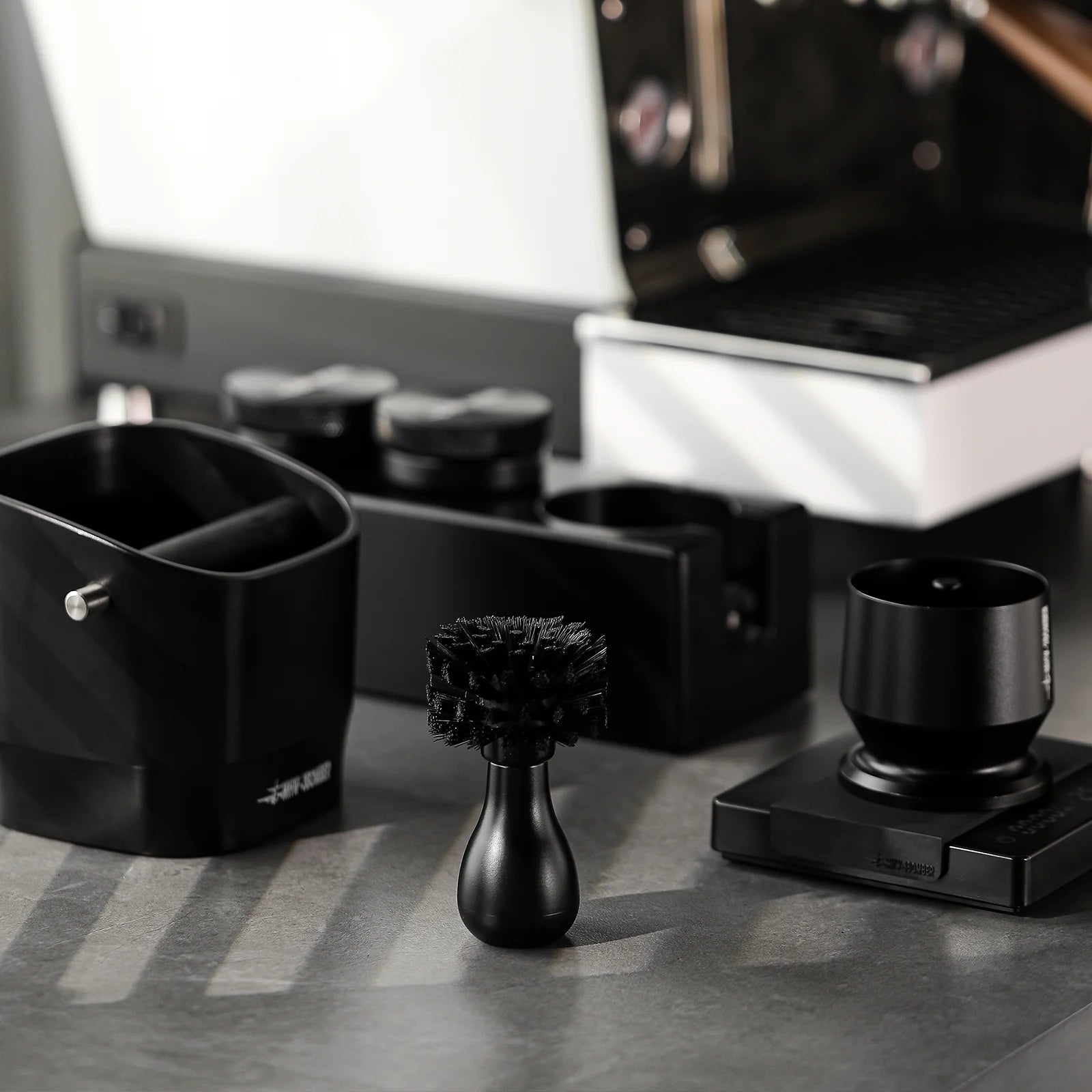 MHW-3BOMBER black coffee portafilter cleaning brush and other barista tools.